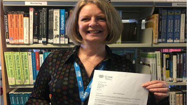 Tutor Carol Laing holding up a letter of commendation from CIM