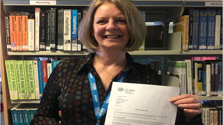 Tutor Carol Laing holding up a letter of commendation from CIM