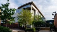 Exterior view of the UCEN Manchester Nicholls campus building surrounded by trees and landscaped walkways.