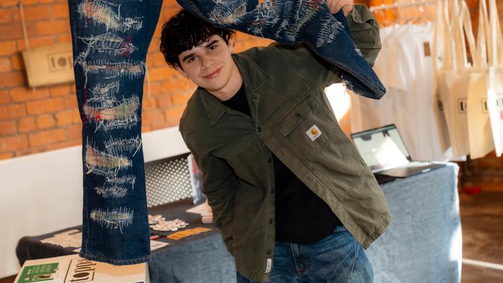 Photograph of Graphic Design & Branding student alongside their work at end of year show.