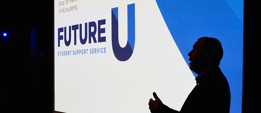 Silhouette of a person speaking in front of a large screen displaying the Future U Student Support Service logo.