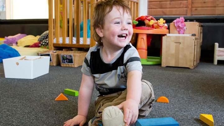 A young child laughing and playing with toys