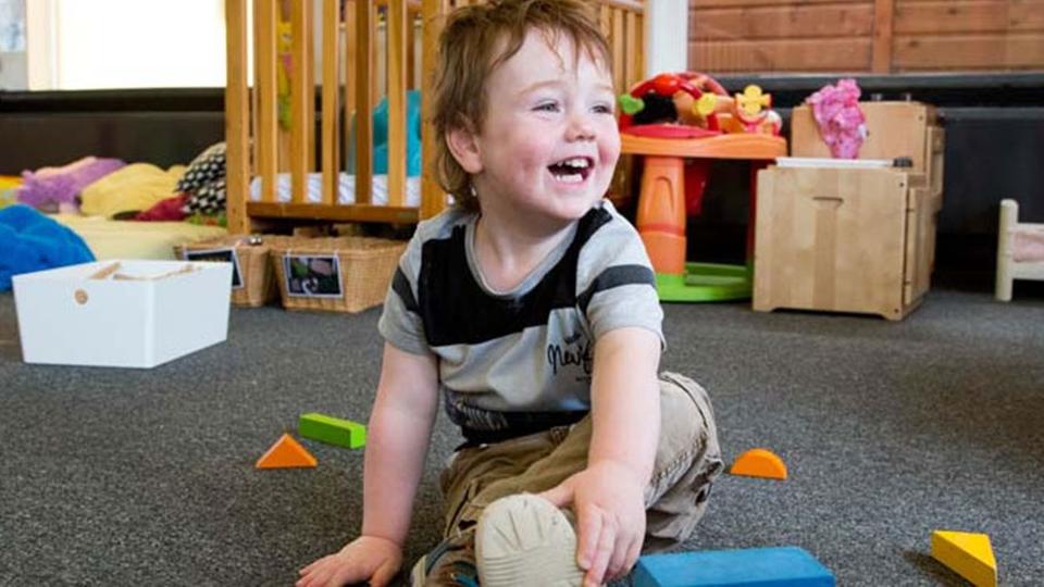 A young child laughing and playing with toys