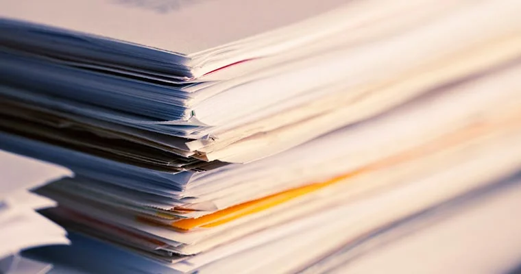 Stack of paper documents and folders arranged in a pile.