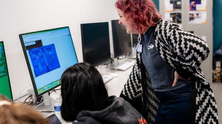 UCEN Manchester Teacher reviewing students work on a computer