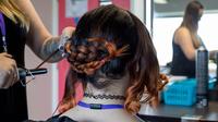 A hairdresser straightening a woman's hair