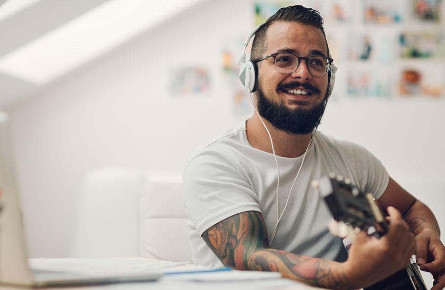 Young man playing guitar while wearing headphones