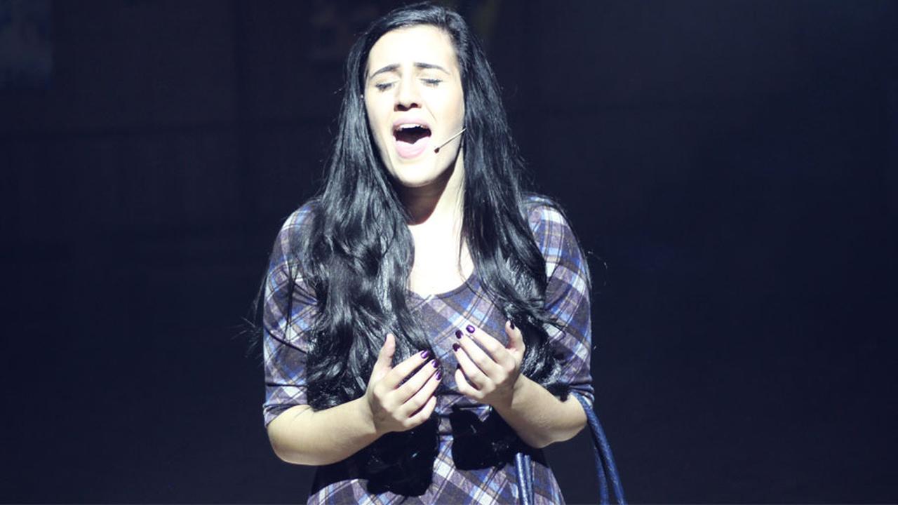 An Arden student singing solo on stage