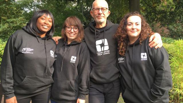 A group of students wearing black hoodies which say manchester film school