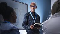 Business student stood presenting in front of two students