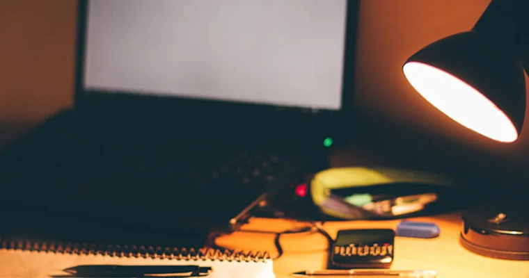 A desk with a lamp and laptop