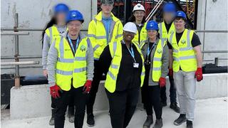 A group of Construction students in high-viz jackets stand on the roof of the Co-op Live construction site in Manchester.