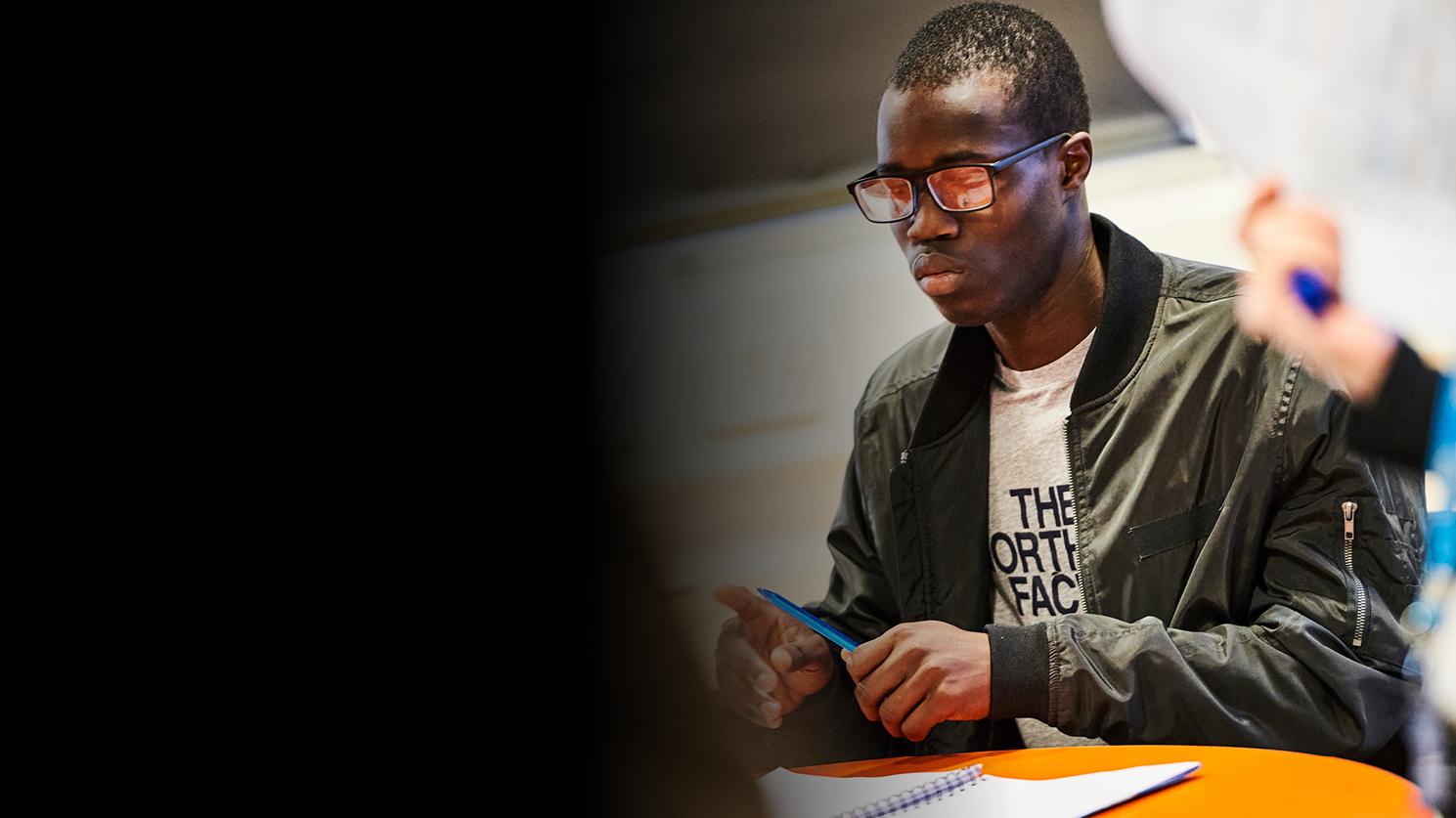 Young man sitting at a desk and taking notes