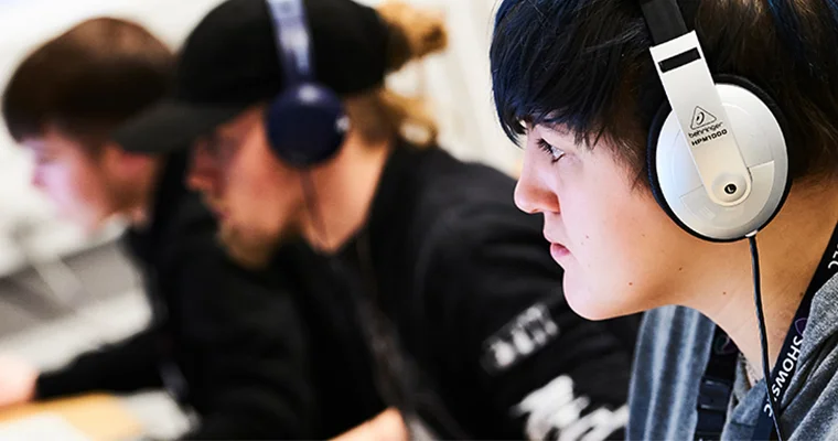 A line of students with headphones on using audio equipment