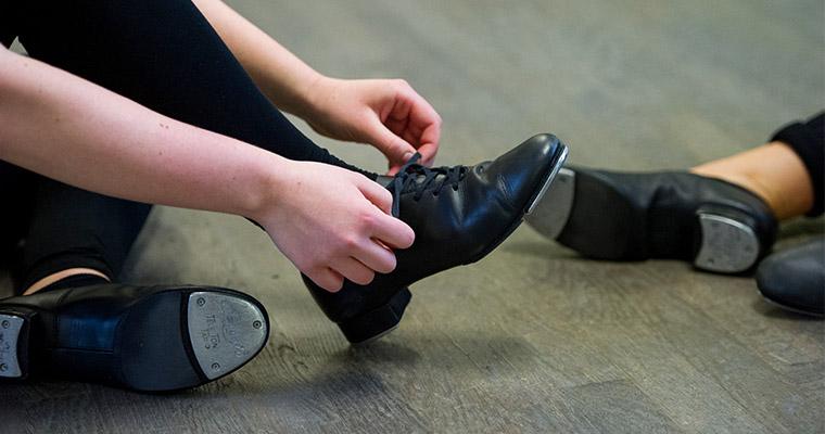 Close up of a person's hands putting on a black shoe