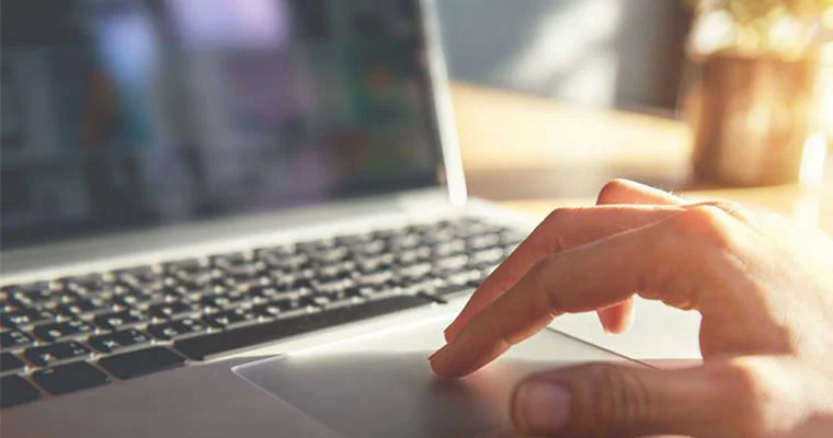 Close up of hands using a laptop trackpad