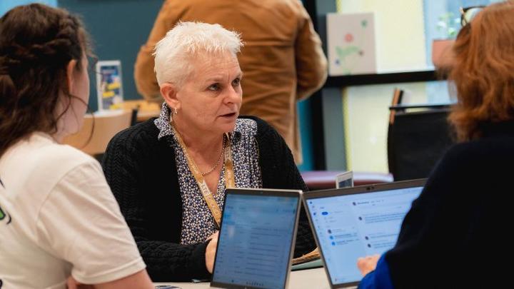 Parent speaking with two people across a table about student finance, with laptops open in a UCEN Manchester learning and advice setting.