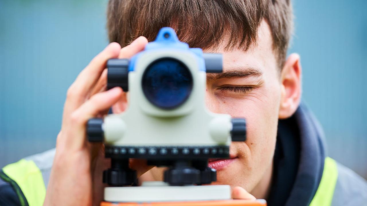 A construction student looks through an automatic level, straight down the camera.