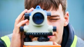 A construction student looks through an automatic level, straight down the camera.