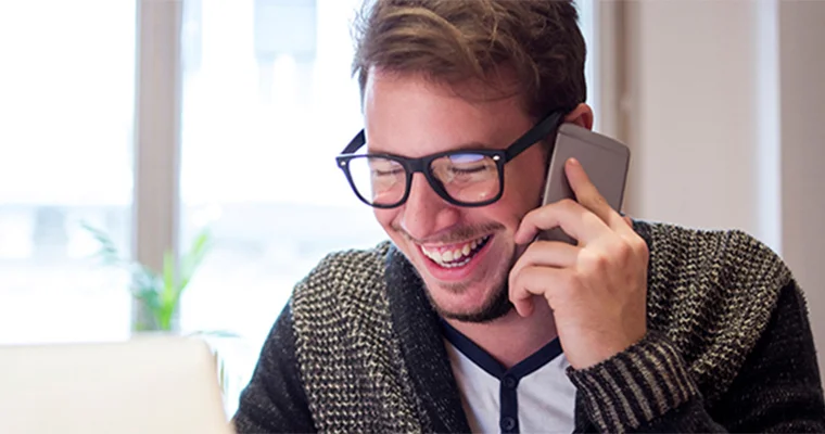 A person smiling while talking on a phone