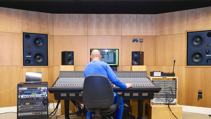 A person sitting at a desk surrounded by sound equipment