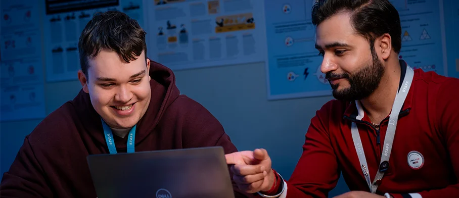 Two people look at a laptop screen
