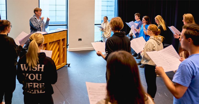 A tutor running through a singing lesson with students