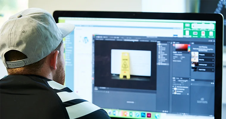 Over-the-shoulder of a student using photoshop on an iMac