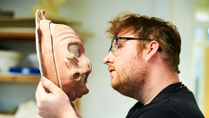 A student looking at a newly create face mould