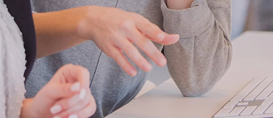 Close-up of two people talking on a computer desk