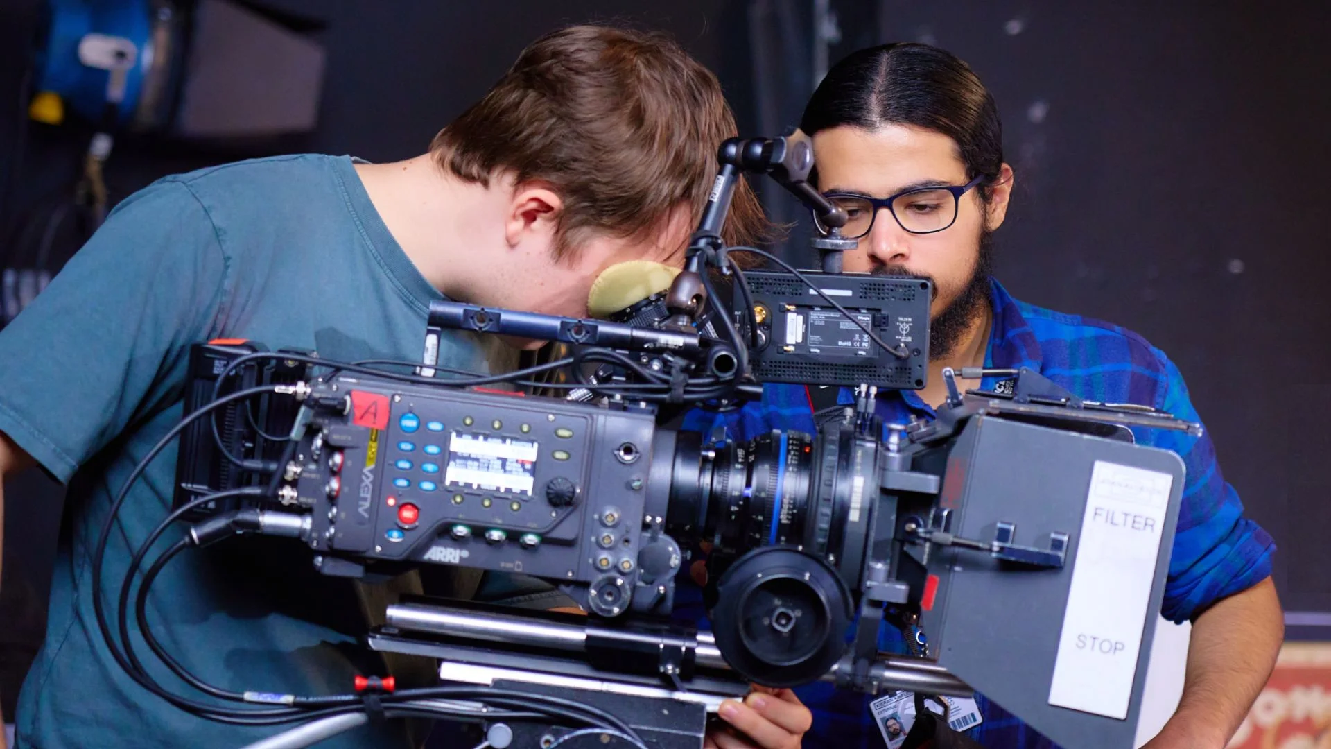 Two people operating and reviewing footage on a professional video camera setup in a film production studio.