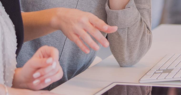 Close-up of two people talking on a computer desk