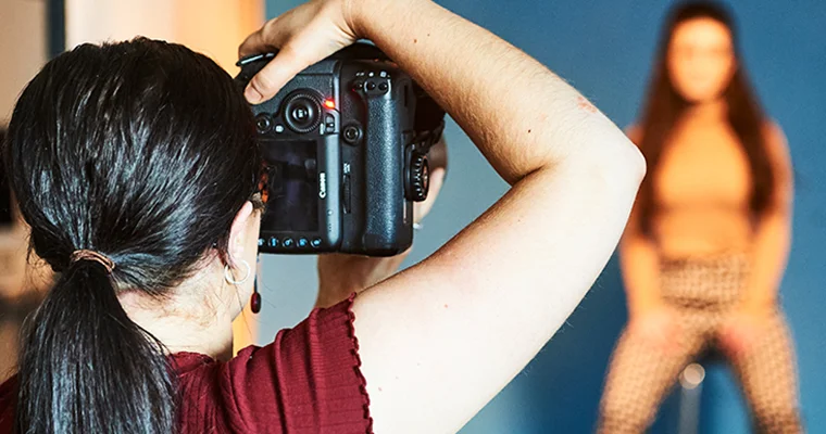 Over-the-shoulder view of a photographer taking a picture of a model