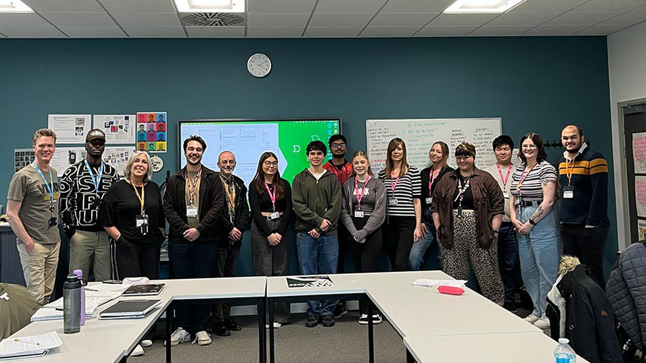 Graphic Design students standing with UNISON staff in a classroom after pitching to them.