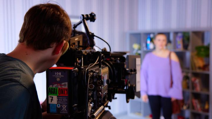 Two young people operating a professional video camera