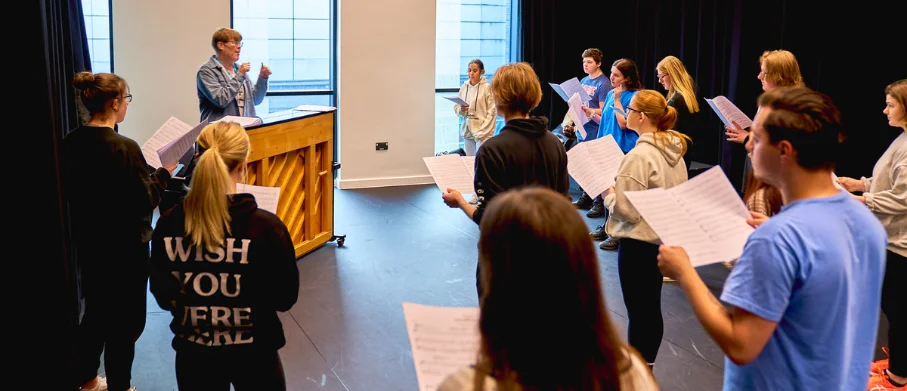 A tutor running through a singing lesson with students