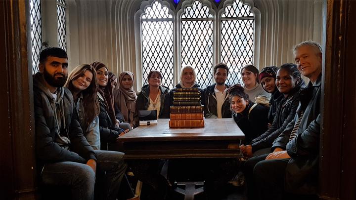 A group of people on a field trip in a room with books on the table