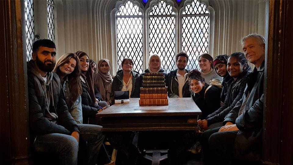 A group of people on a field trip in a room with books on the table