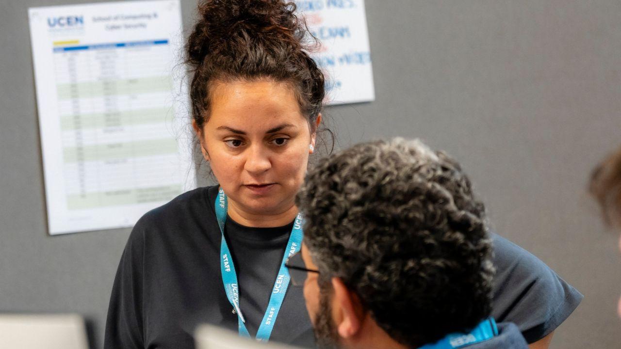 UCEN Manchester staff member speaking with a student in a classroom or office setting.