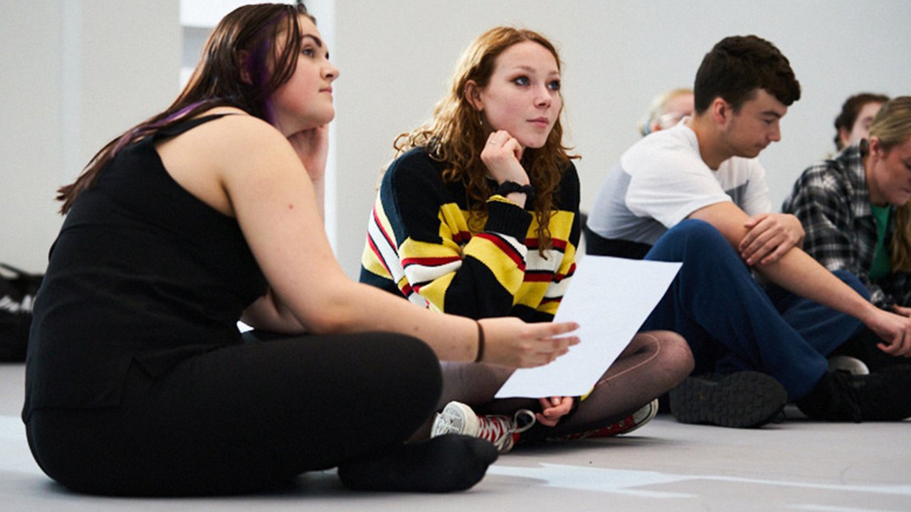 Photograph from a UCEN Manchester open day of two prospective students sat on the floor with their legs crossed.