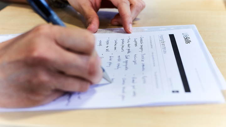 Close-up of someone writing on a pad of paper