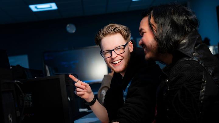 Students working together in a computer suite, seated at desktop computers during a classroom session.